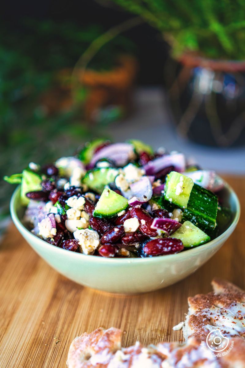 photo of a bowl of kidney bean salad with bread and a plant in the background
