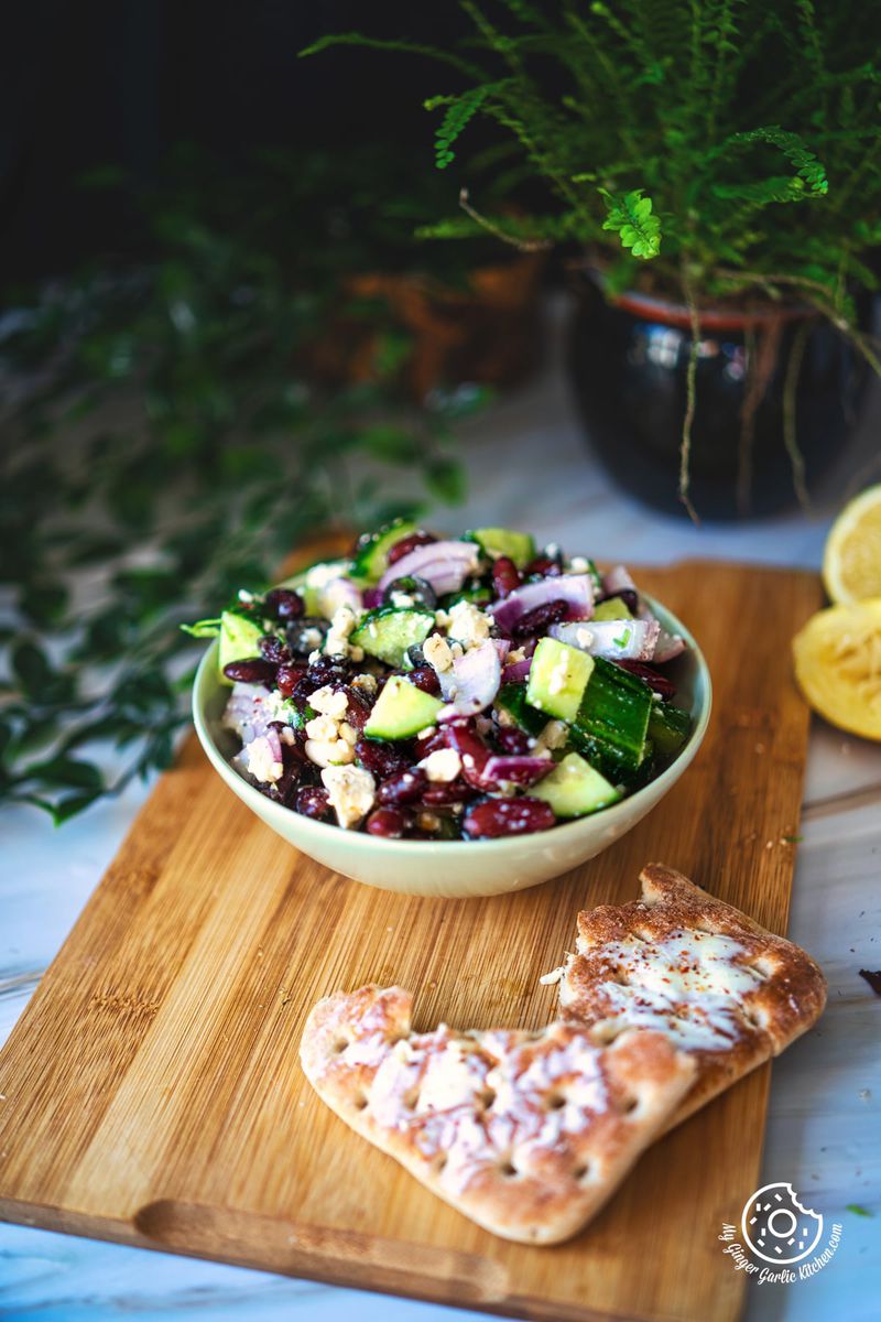 photo of a bowl of kidney bean salad with a slice of bread on a cutting board