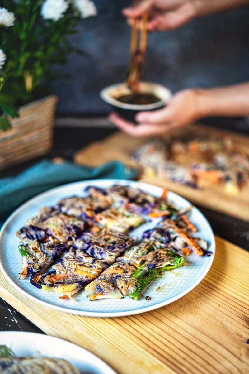 A plate of Korean vegetable pancakes served with a sauce.