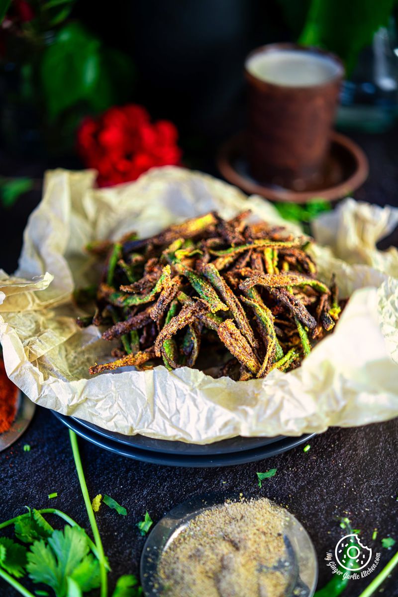 - photo of a plate of fried Kurkuri Bhindi with a red flower in the background