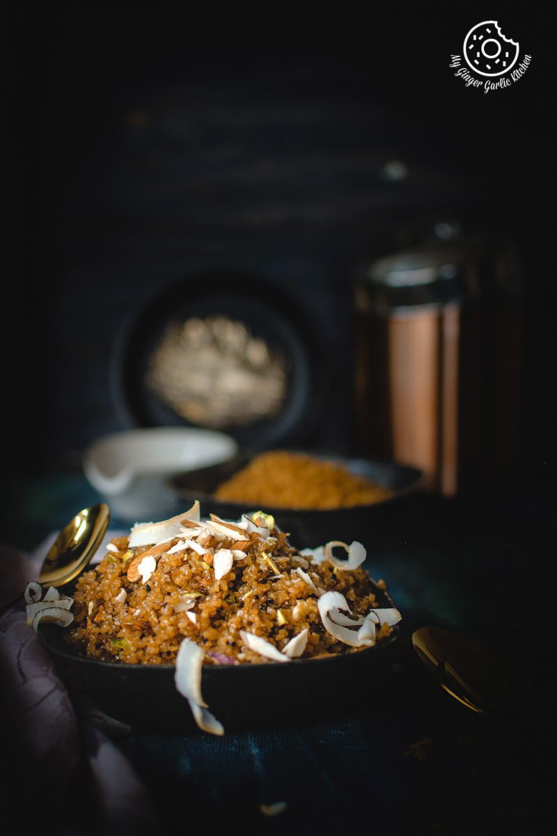 a plate of rajasthani lapsi with coconut and nuts and a golden spoon