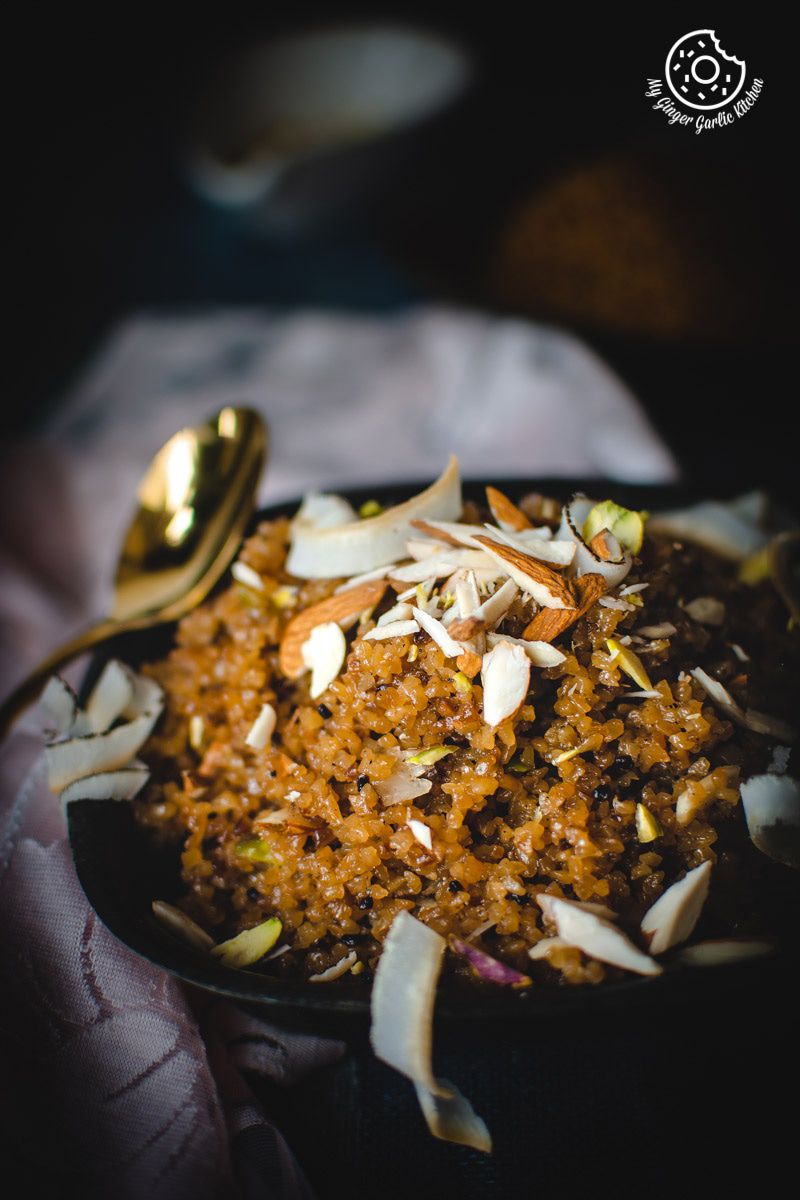 there is a bowl of rajasthani lapsi with coconut and nuts with a spoon
