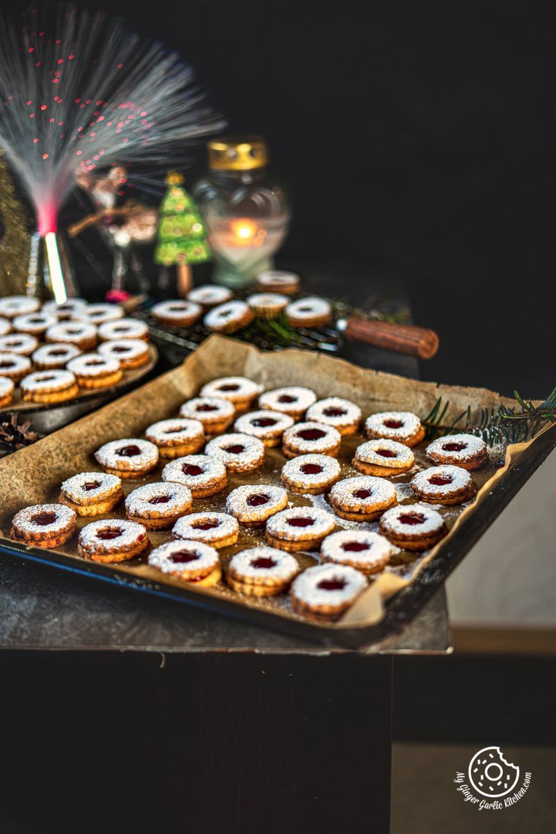 sugar dusted linzer cookies in a baking sheet and some on the side