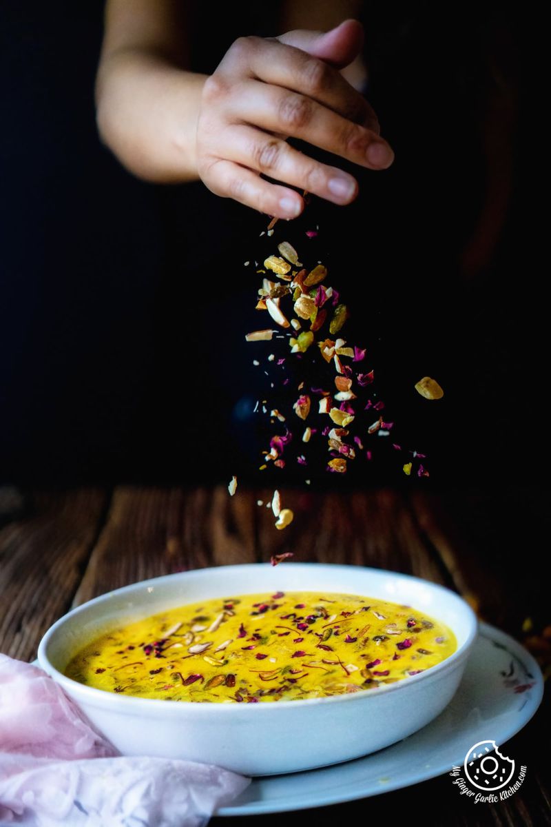 a hand sprinkling dry fruits over makhane ki kheer bowl