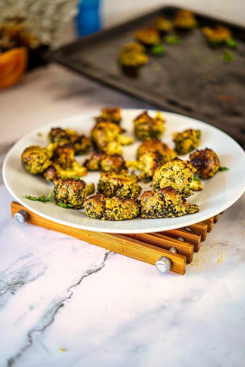 Plate of golden-brown malai broccoli pieces on a wooden trivet.