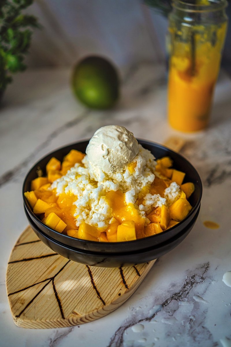Mango Bingsu topped with vanilla ice cream, fresh mango chunks, and mango puree, a refreshing Korean shaved ice dessert