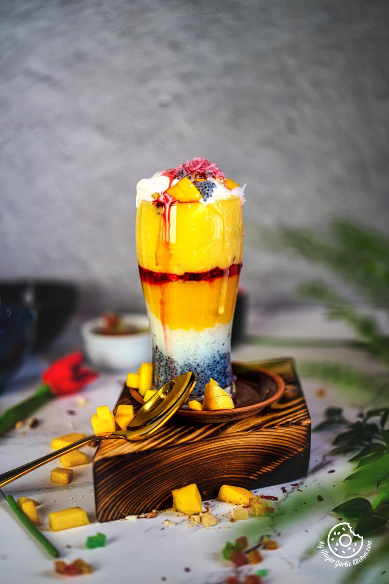 photo of a mango falooda dessert drink and a spoon rest on a table
