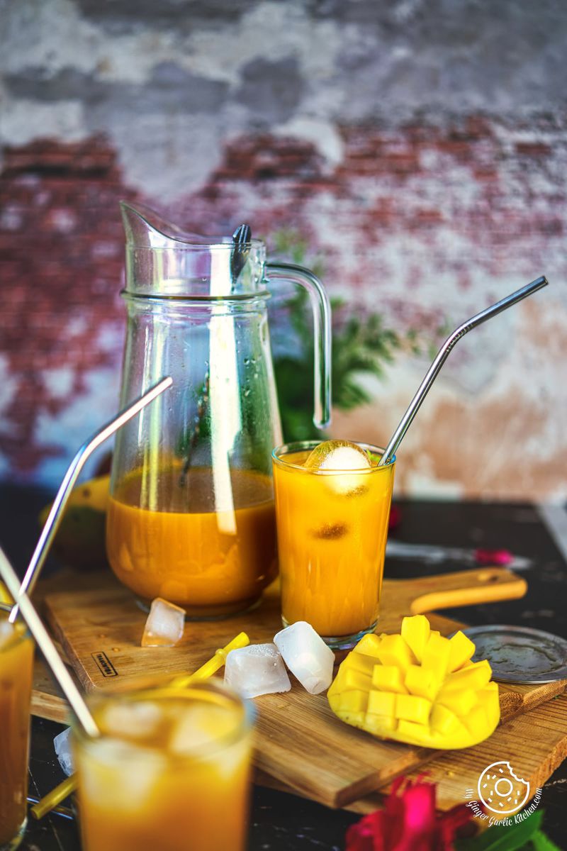 mango iced tea in a glass with a glass pitcher on the side