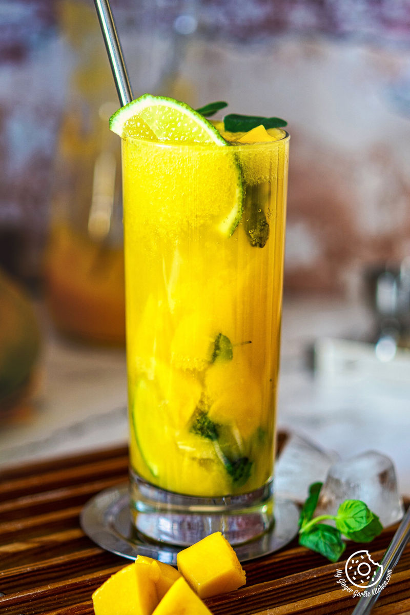 photo of a glass of mango mojito with a straw and a lime slice