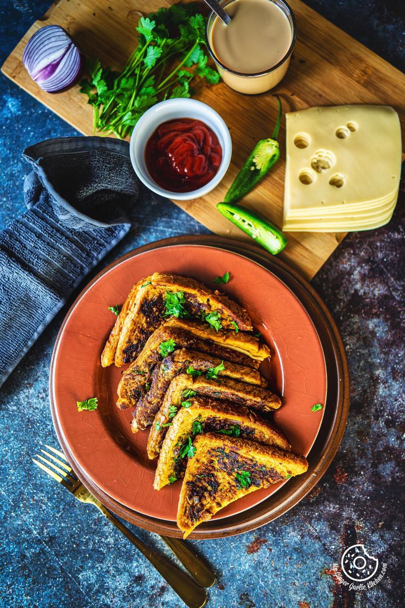 overhead shot of masala french toast in a brown plate with cheese and tomato ketchup on the side