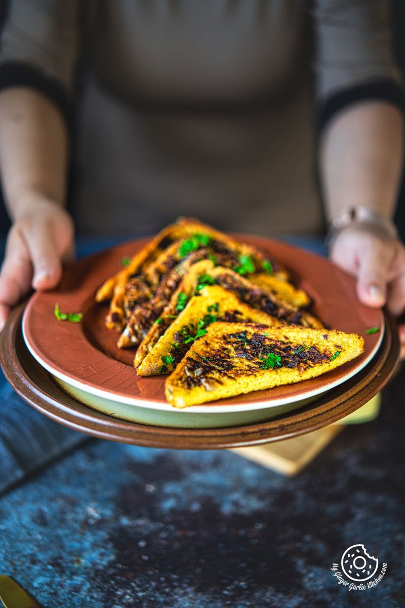 a female holing a plate with masala french toast