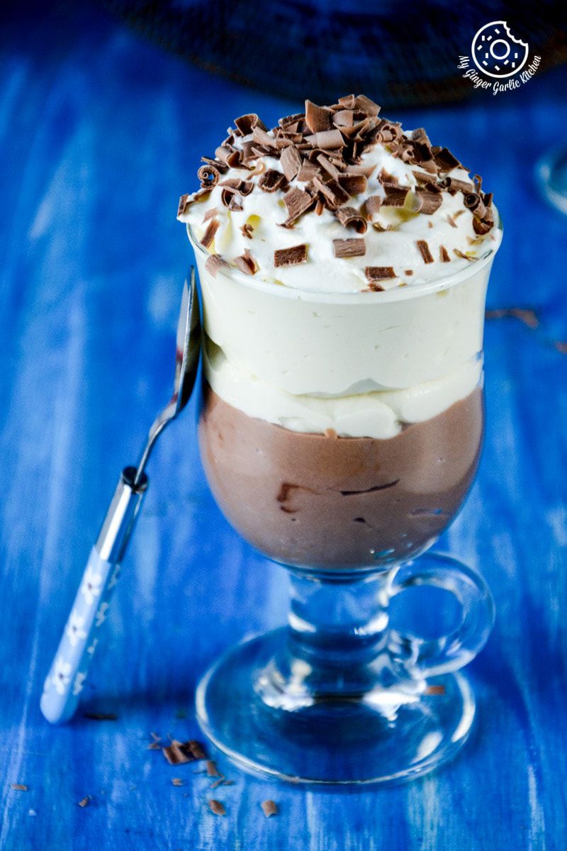 a mascarpone cream cheese chocolate mousse in a glass with a spoon on a blue table