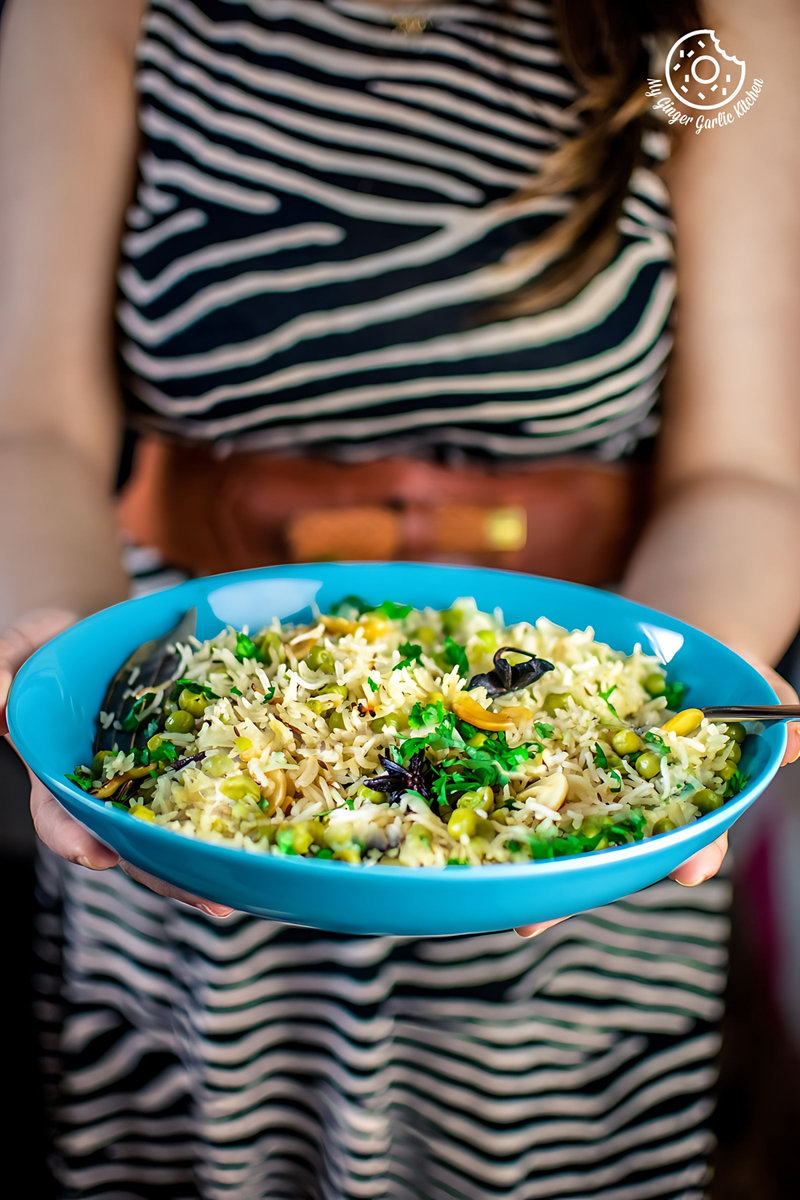 a female holding a plate of matar pulao