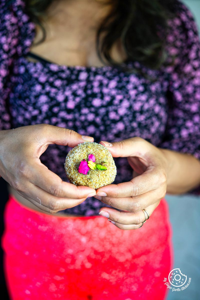 photo of a woman holding a mathura peda with a flower on it