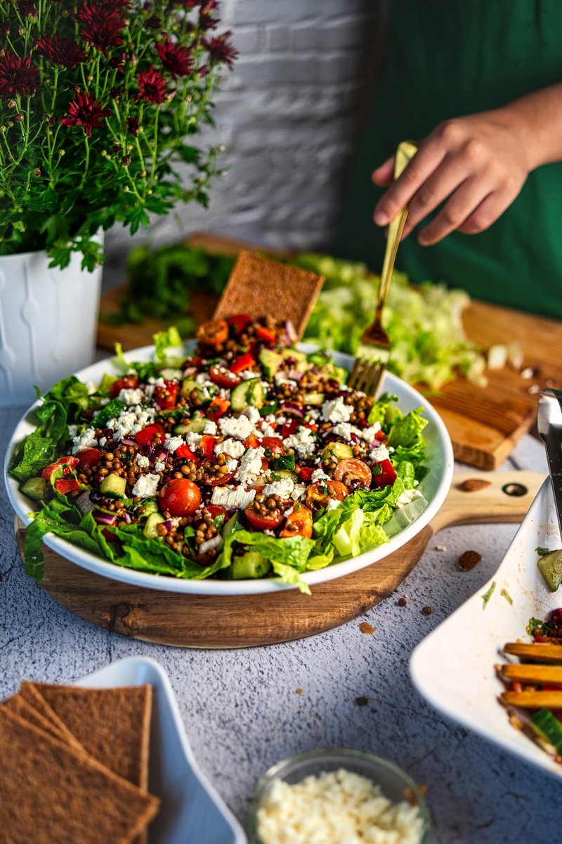 Mediterranean lentil salad served with feta, pomegranate, fresh vegetables, and crisp romaine lettuce