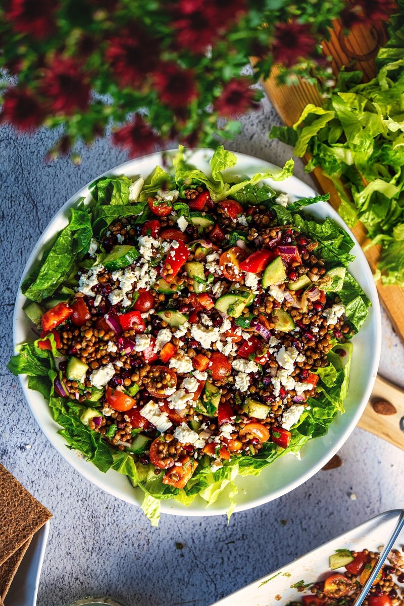 Mediterranean lentil salad with feta and pomegranate served in a bowl with fresh vegetables and herbs