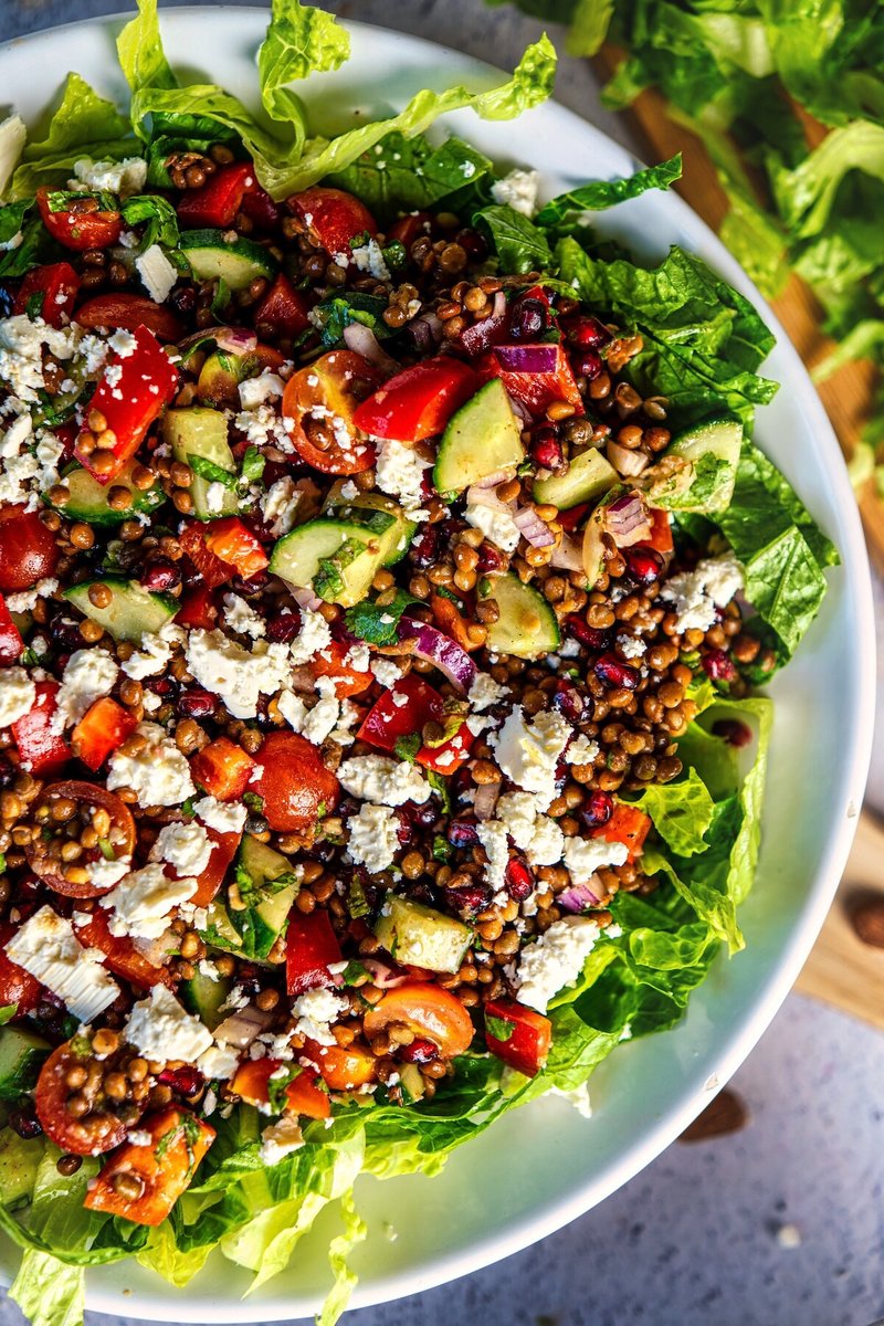 Close-up of Mediterranean lentil salad with cucumber, tomatoes, pomegranate, feta, red onion, and herbs