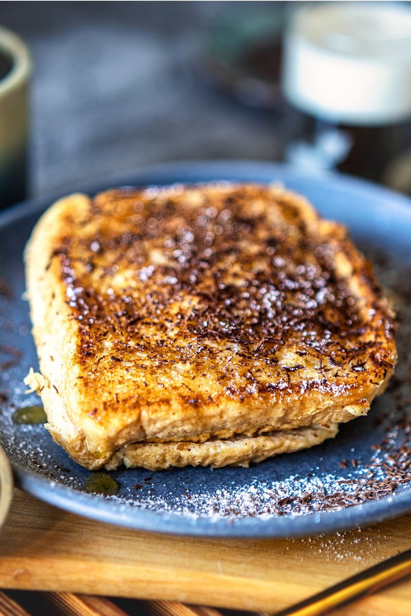 Side view of soft and moist milk toast topped with chocolate shavings, served on a blue plate, perfect for a comforting breakfast.