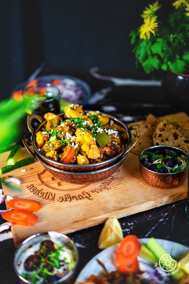 mix veg garnished with coriander on a wooden board with grapes raita on the side