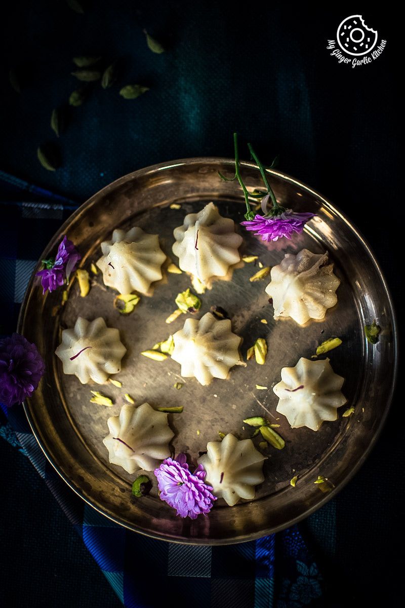 some steamed modaks on a brass plate with purple flowers