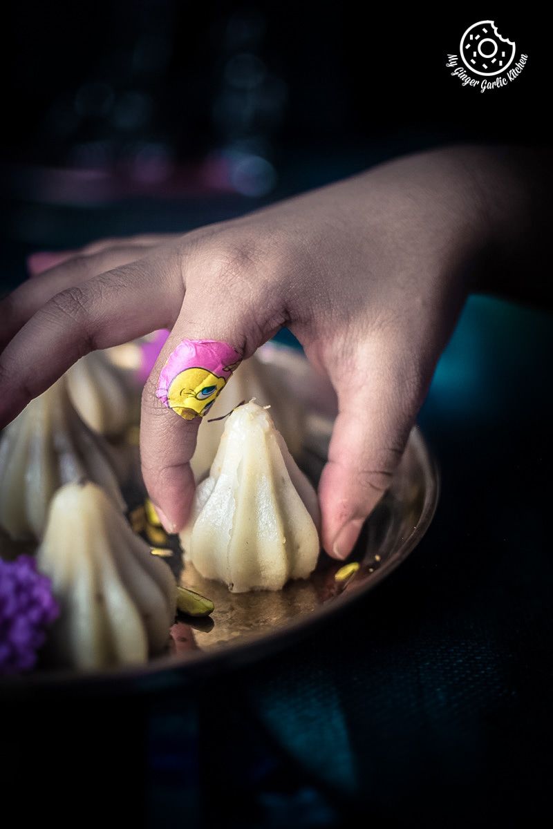 someone is picking a ukadiche modak from a plate of ukadiche or steamed modak