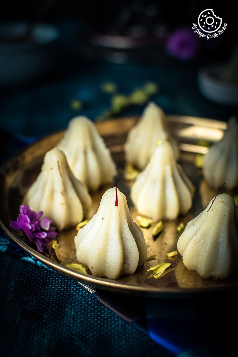 ukadiche or steamed modaks topped with saffron strands kept on a plate with flowers