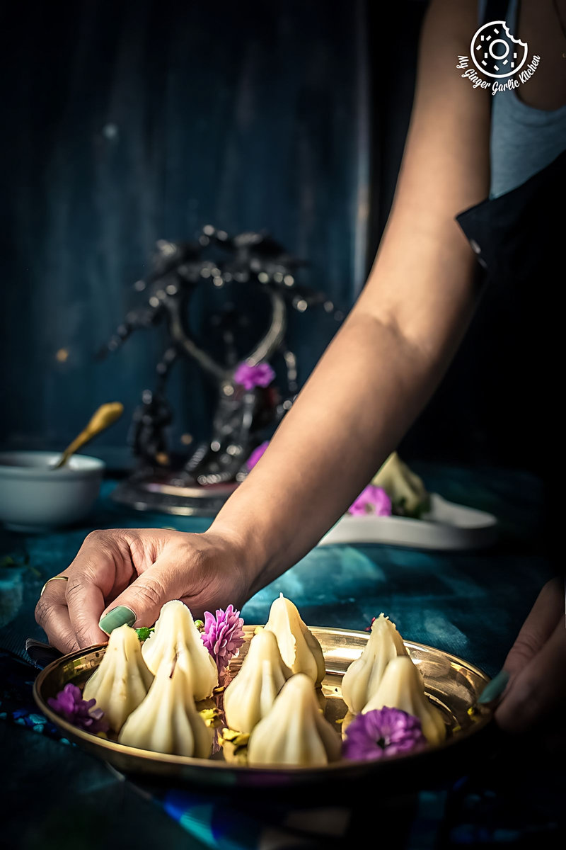 someone is holding a plate of ukadiche or steamed modak with purple flowers