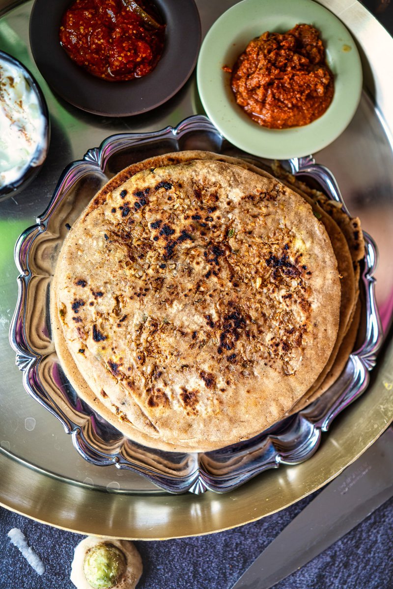 A plate of Mooli Paratha or Radish Paratha served with assorted chutneys and yogurt.