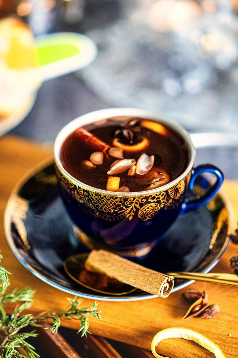 Warm holiday mulled berry juice served in an elegant cup with cinnamon and orange peel, cozy non-alcoholic winter drink recipe