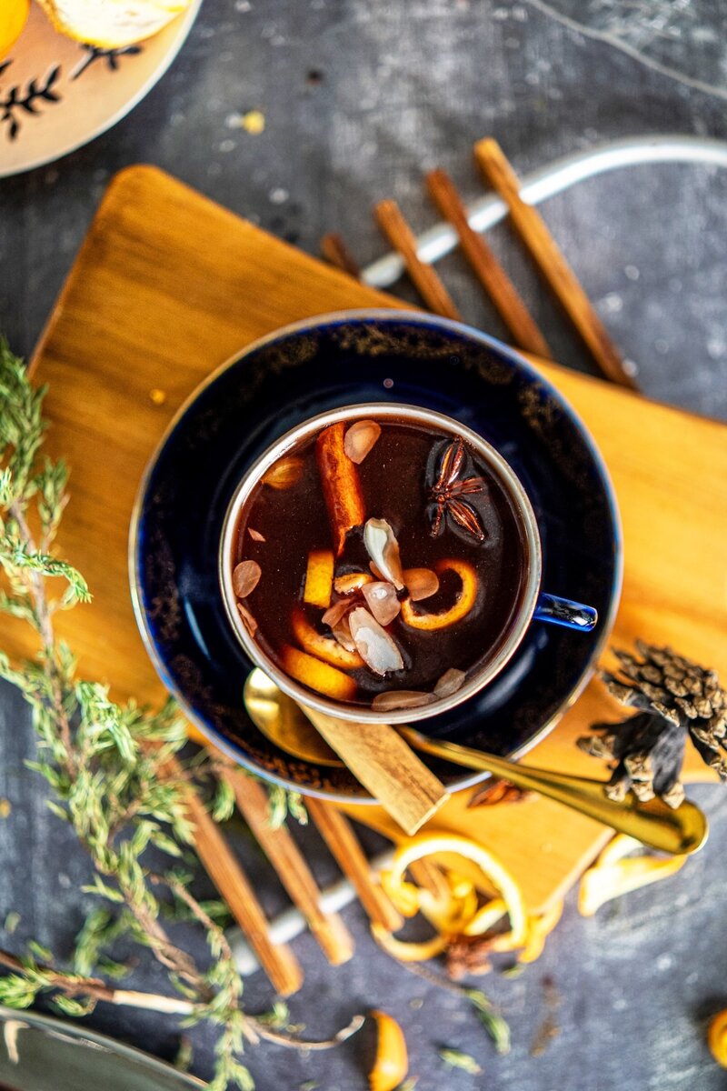 Top view of spiced berry juice with almond flakes, dried cranberries, cinnamon stick, and orange peel, homemade mulled berry juice