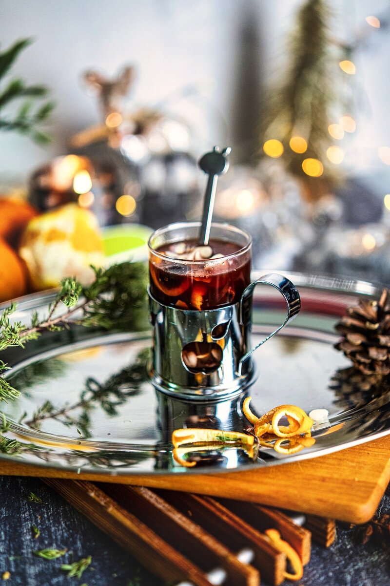 Festive mulled berry juice in a glass mug with orange peel curls, cinnamon, and holiday spices, a warm spiced berry juice drink for winter