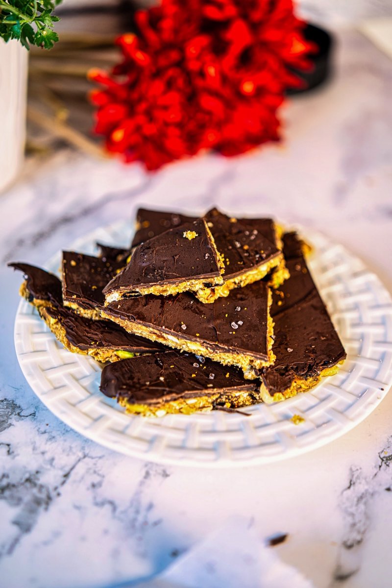 Stack of homemade no-bake almond energy bars with a chewy dried fruit and nut filling and dark chocolate topping.