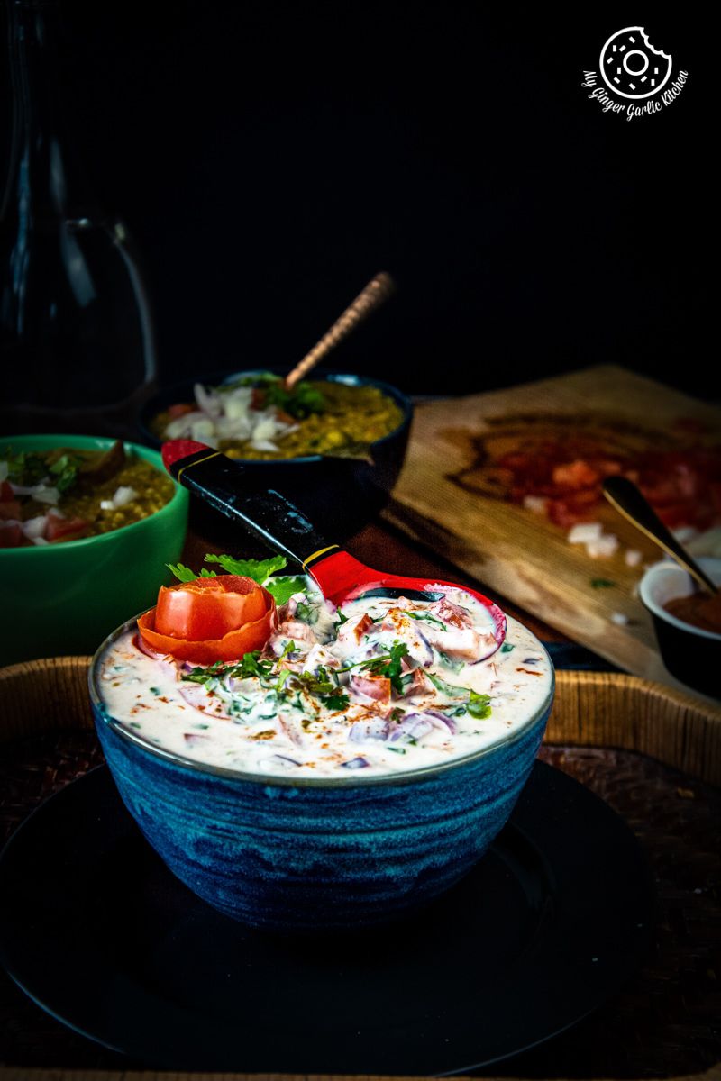 onion tomato raita served in a blue ceramic bowl