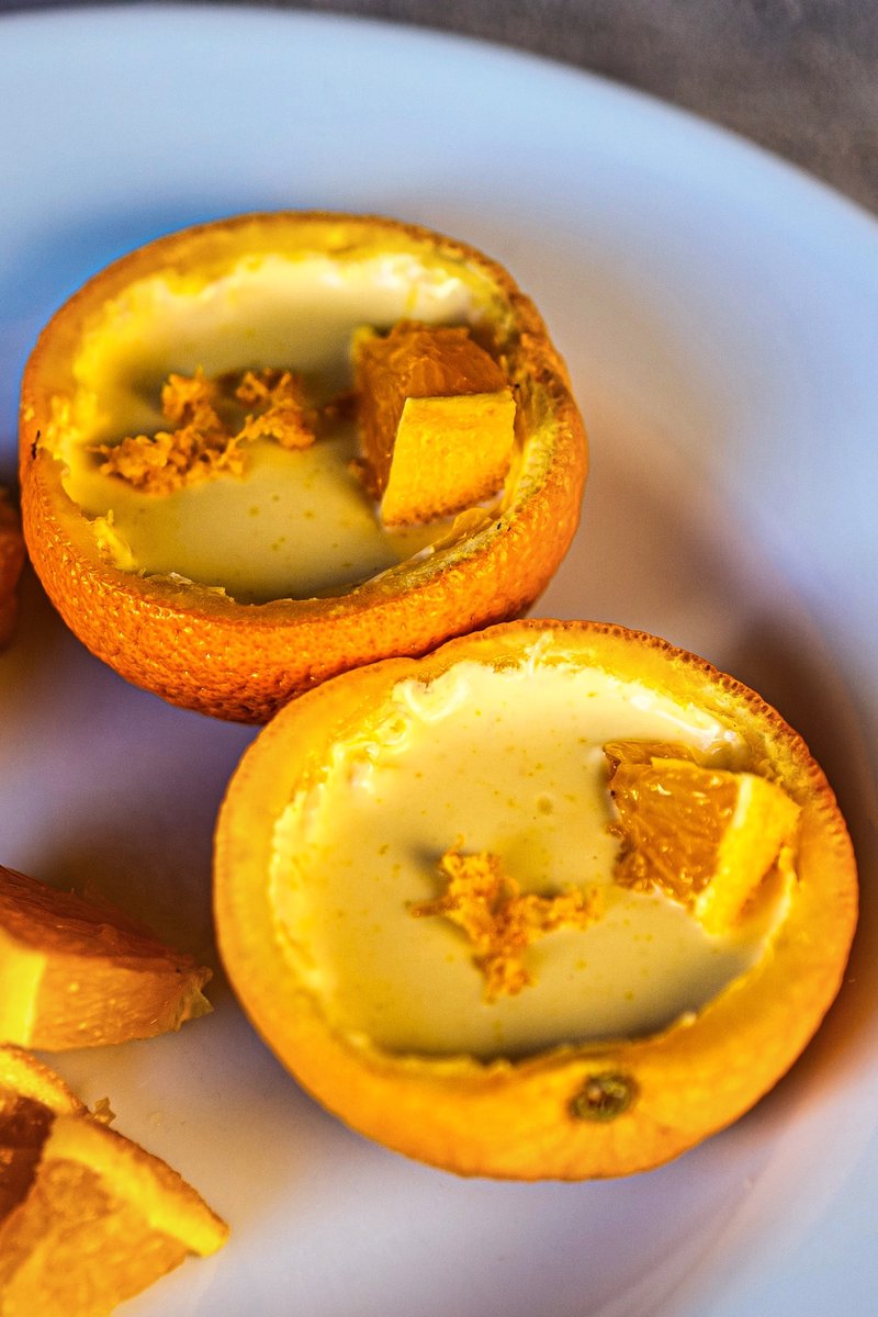 Close-up of homemade orange posset with creamy citrus filling served inside orange shells for an elegant no-bake dessert.