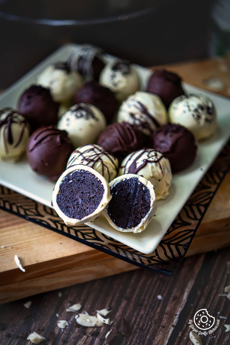 oreo truffle cut into half with more truffles on a yellow square plate