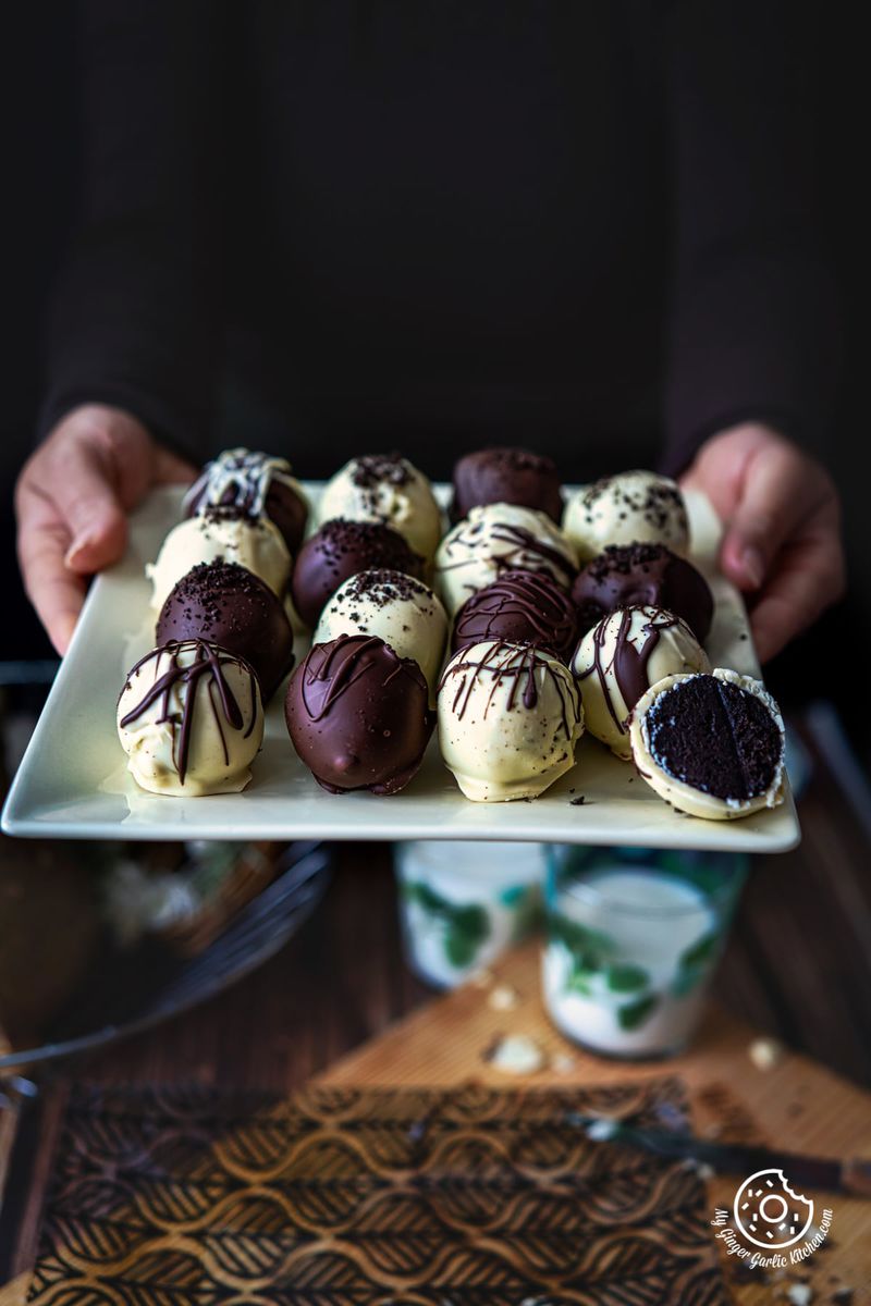 a female holding a yellow square plate filled with oreo truffles