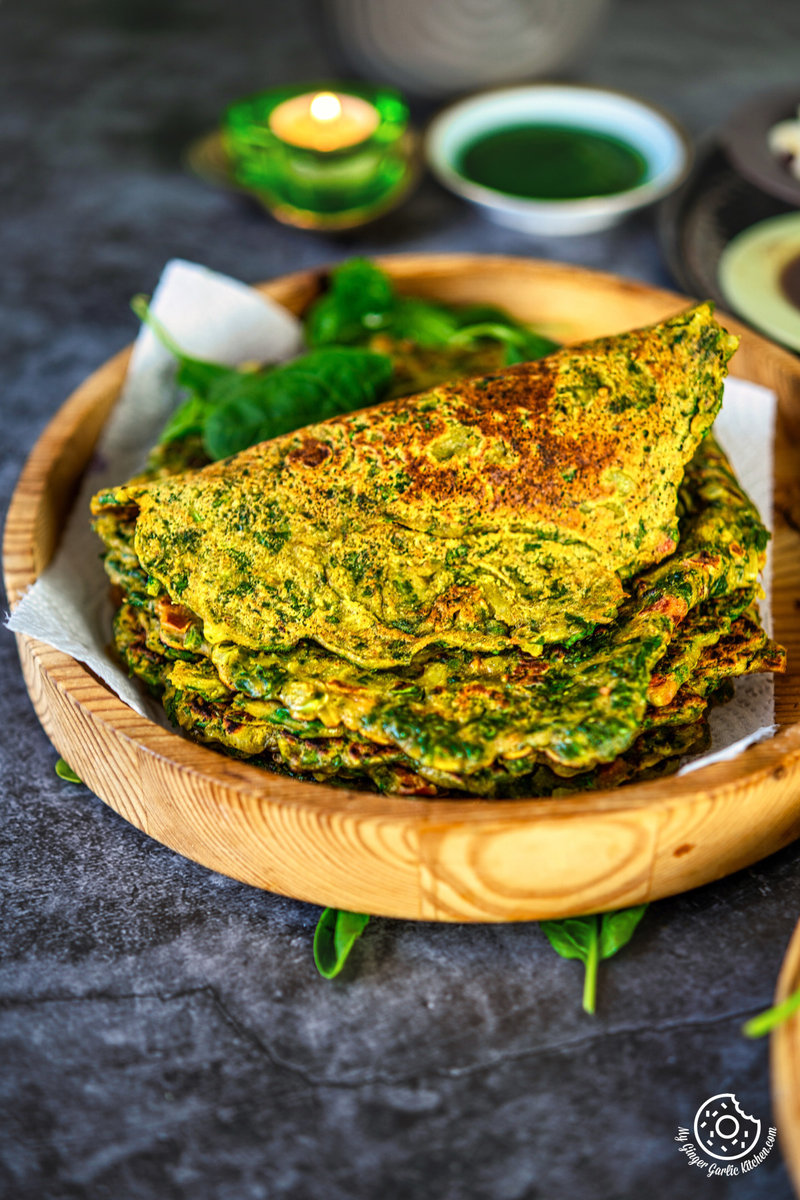 a wooden plate of palak cheela that is on a table