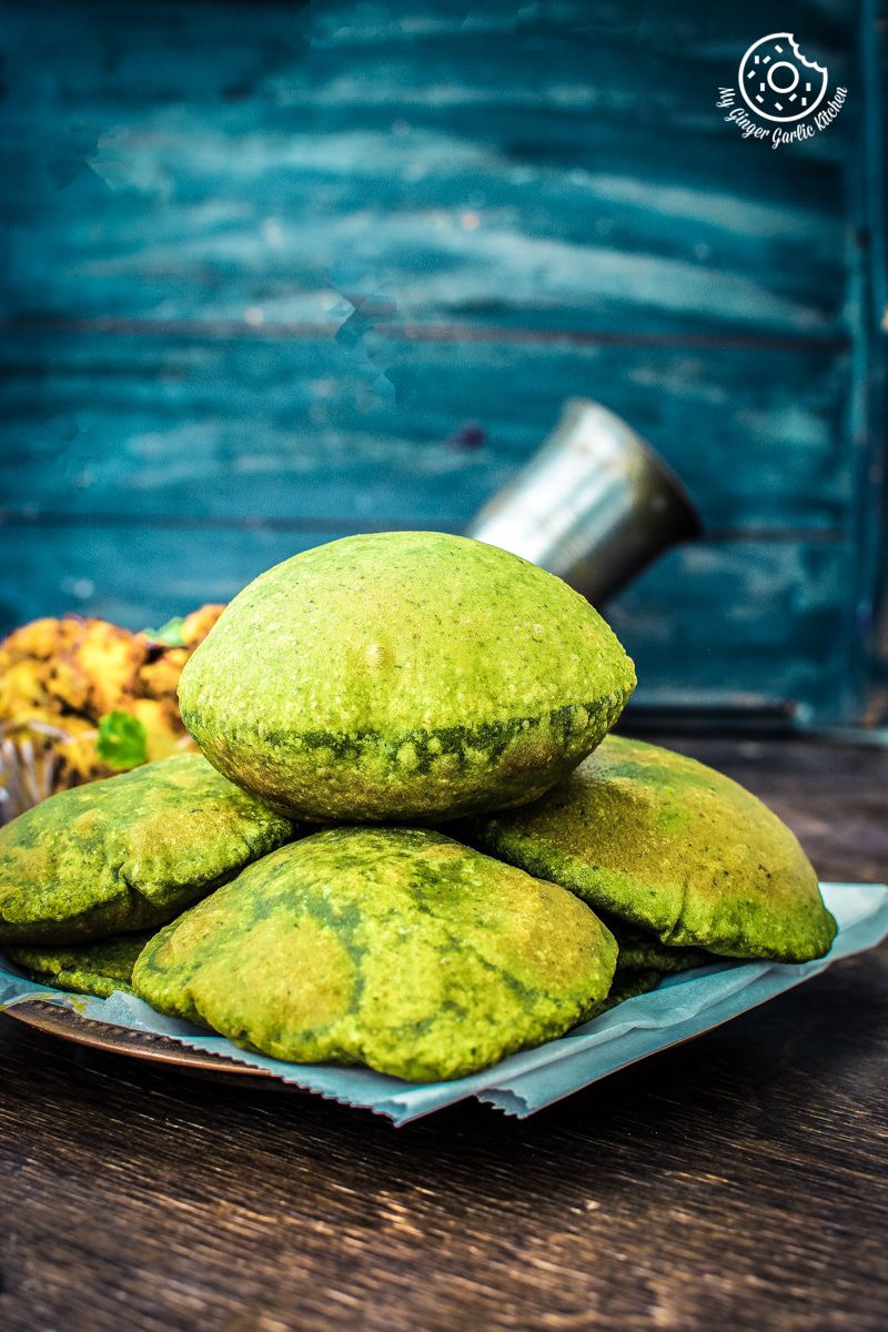 a plate of green palak puris on a table