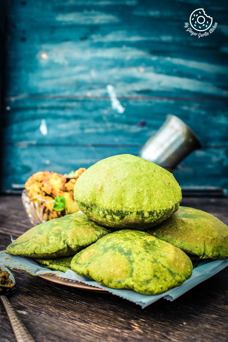 a bunch puffed palak puri on a plate on a table