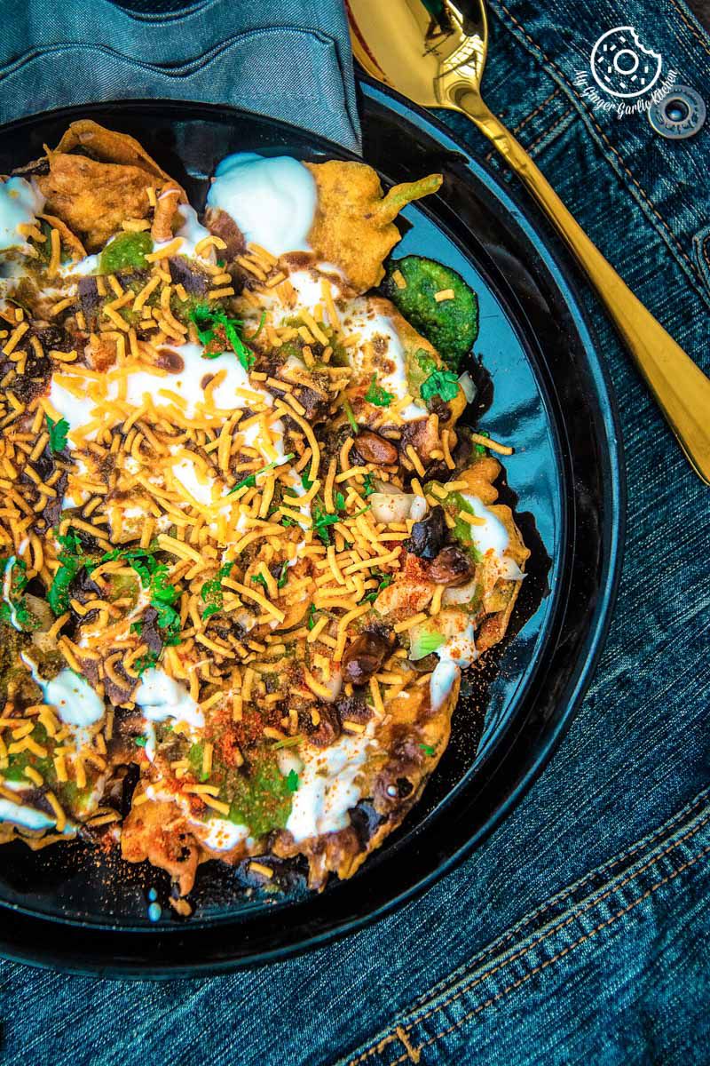 palak patta chaat in a black plate with a spoon and a napkin