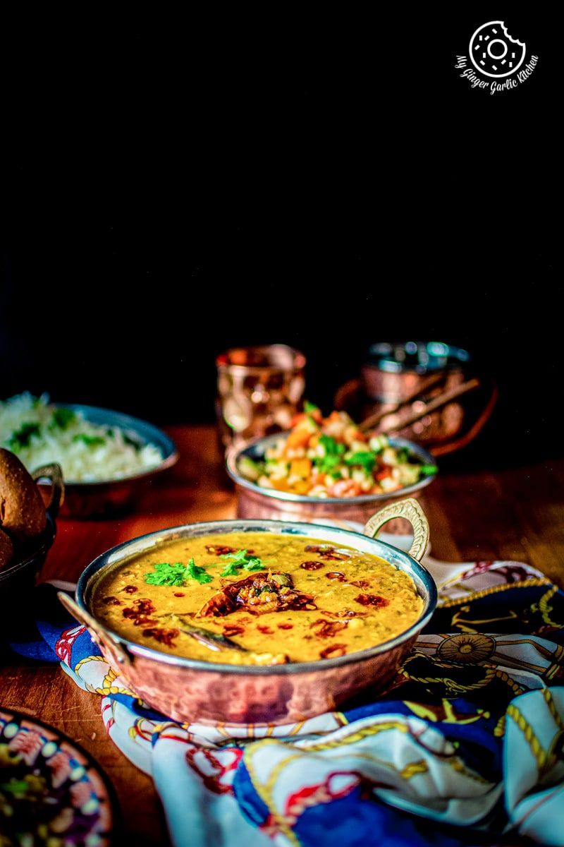 panchmel dal served in a copper kadahi and a copper salad bowl in backdrop