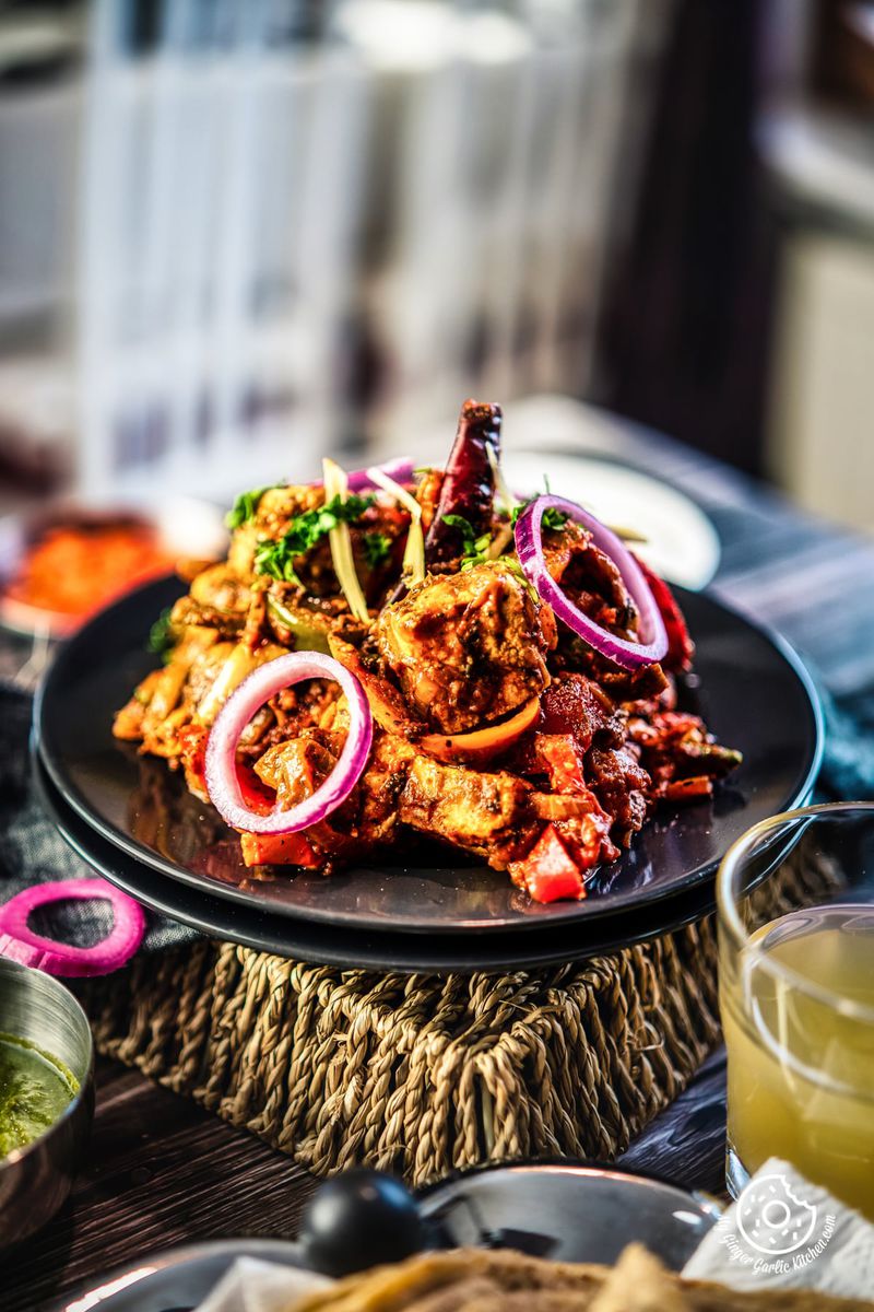 paneer jalfrezi garnished with onion rings and cilantro served in a grey plate
