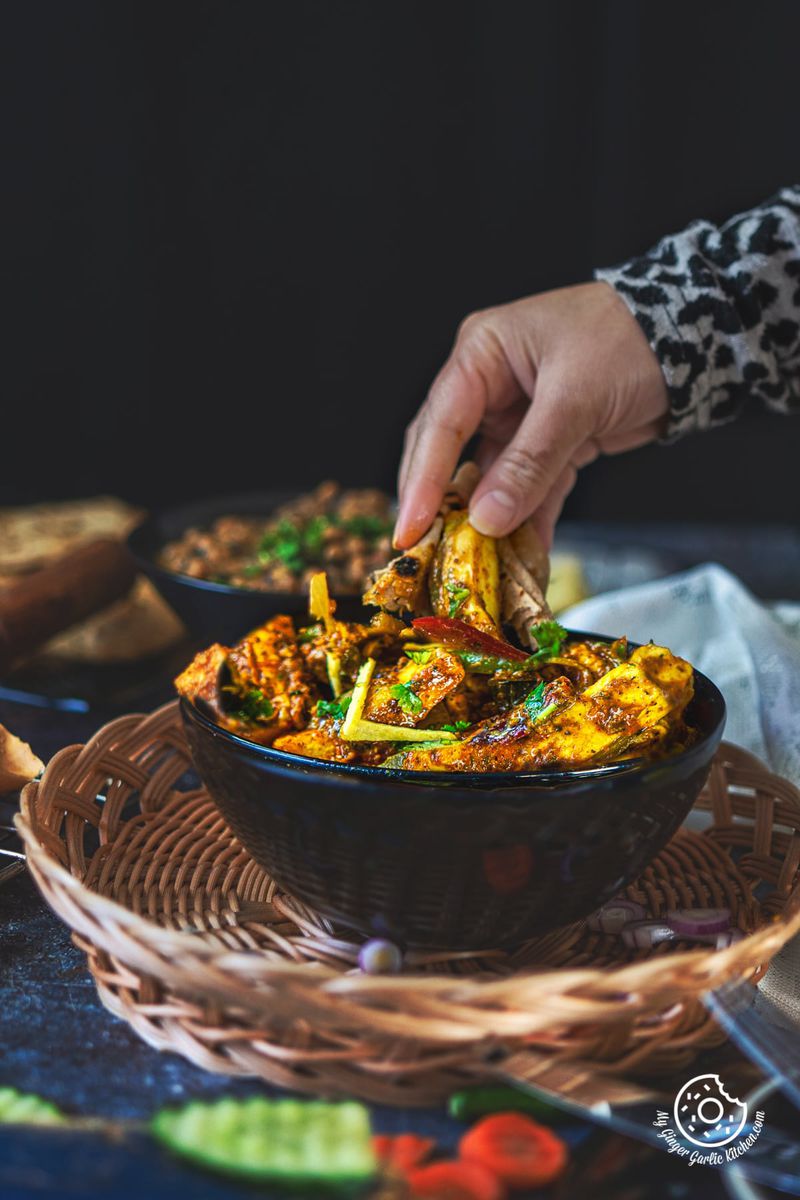 a hand scooping paneer khurchan from the black bowl