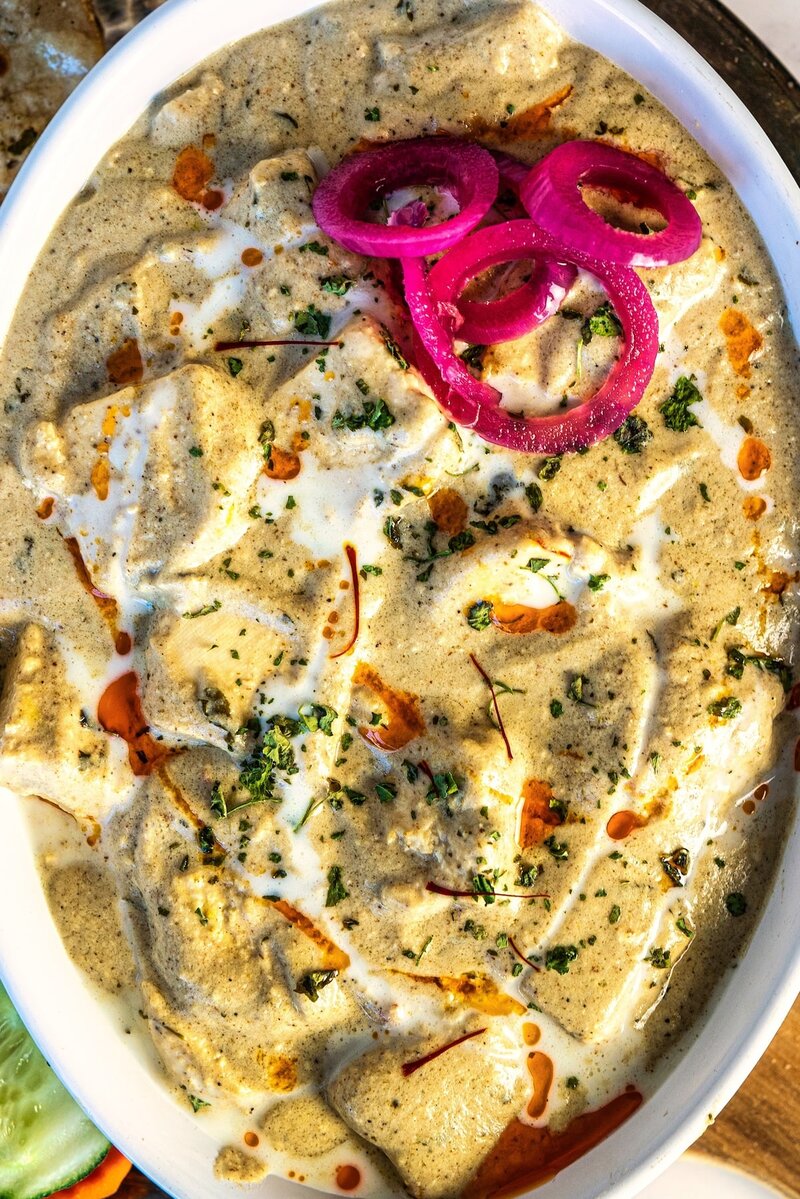 Close-up of paneer nawabi creamy white gravy curry topped with cream and spices, rich paneer curry without tomato