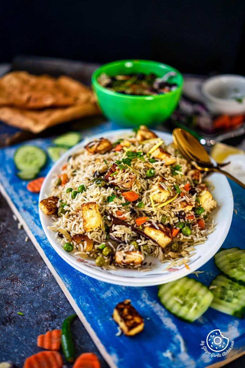 paneer pulao served on a white plate with a side of raita