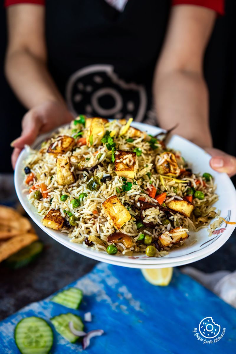 closeup shot of a female holding paneer pulao plate