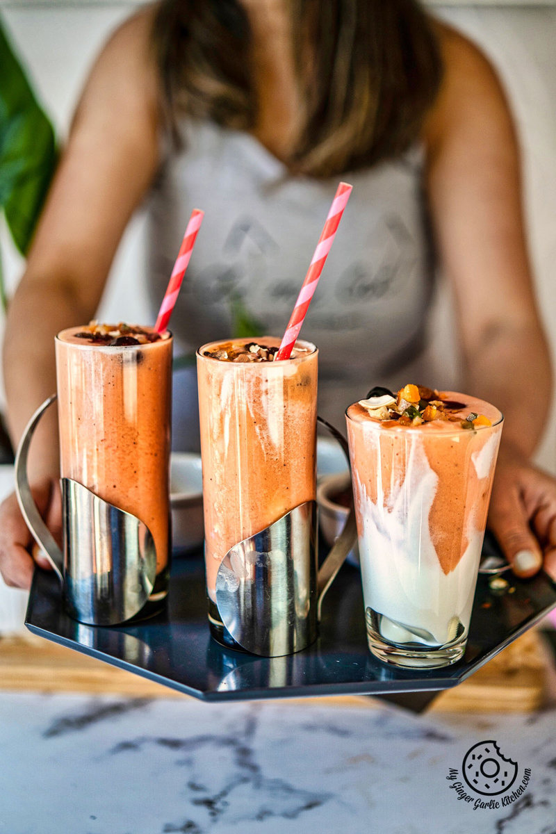 a female holding a plate with three papaya shake glasses