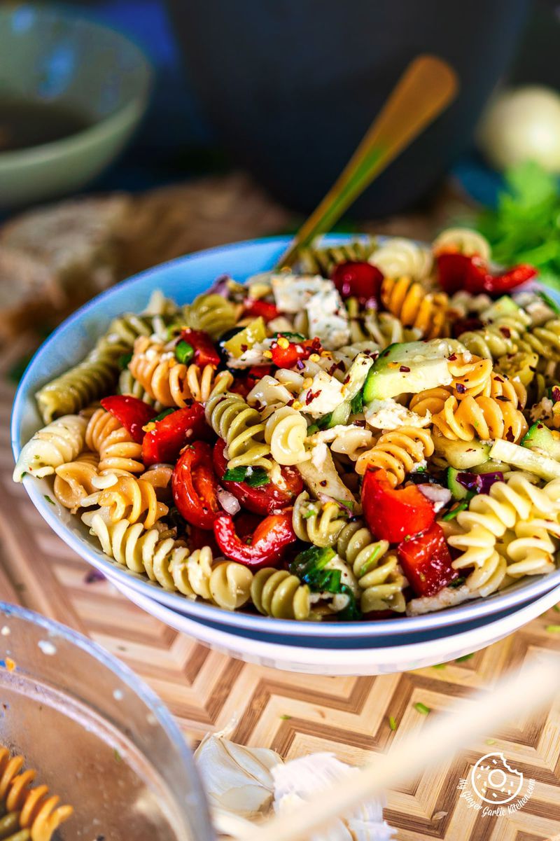 closeup photo of a bowl of pasta salad with tomatoes and other vegetables