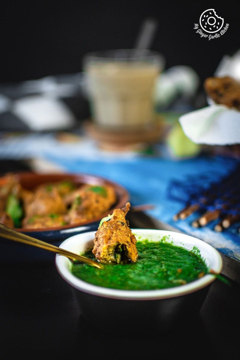 a bowl of green chutney with a paush vada and spoon in it