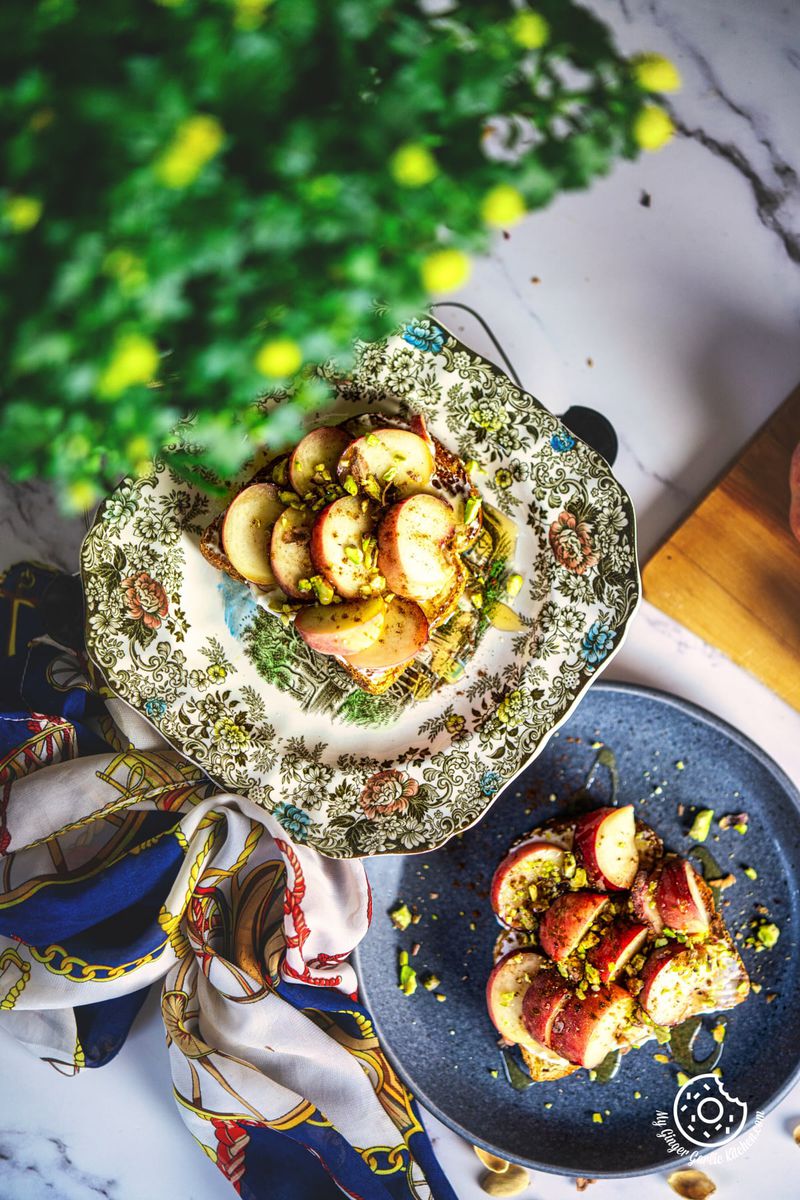 photo of a plate of peach toast with peaches and pistachios on it